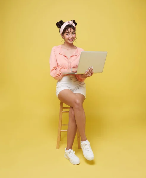 Χαρούμενη Νεαρή Ασιάτισσα Που Χαμογελάει Ενώ Χρησιμοποιεί Φορητό Υπολογιστή Κάθεται — Φωτογραφία Αρχείου