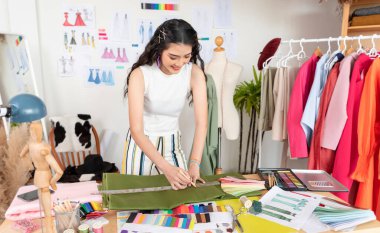Asyalı terzi kadın terzide terzi atölyesinde çalışıyor, güzel bayan moda tasarımcısı atölyede yeni el yapımı elbiseler dikiyor..