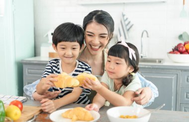 Asyalı bekar anne, oğlu ve kızı mutfakta. Aile aktivitelerinin tadını çıkarın..