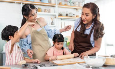 Mutlu Asyalı aile evde hamur hazırlıyor ve kurabiye pişiriyor. Aile aktivitelerinin tadını çıkarın..