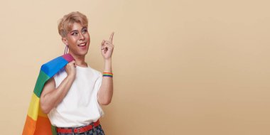 Youth asian transgender LGBT standing with finger pointing isolated over nude color background with copy space. 