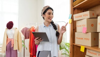 Başarılı girişimci Asyalı genç bayan çek siparişi mağazada kıyafet satar. başlangıçta küçük işletme sahibi, KOBİ veya işletme çevrimiçi ve dağıtım kavramı.