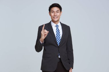 Genç Asyalı işadamının portresi. İyi görünümlü ve özgüvenli. Stüdyonun beyaz arka planında tek başına duruyor..