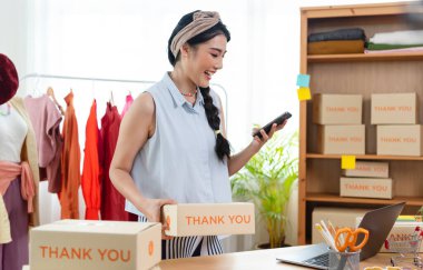 Başarılı girişimci Asyalı genç kadın sipariş verdi, akıllı telefondan elbise sattı. başlangıçta küçük işletme sahibi, KOBİ veya işletme çevrimiçi ve dağıtım kavramı.