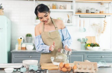 Genç Asyalı ev hanımı mutfakta fırın hamuru pişiriyor..