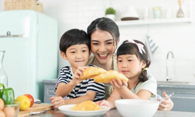 Asyalı bekar anne, oğlu ve kızı mutfakta. Aile aktivitelerinin tadını çıkarın..