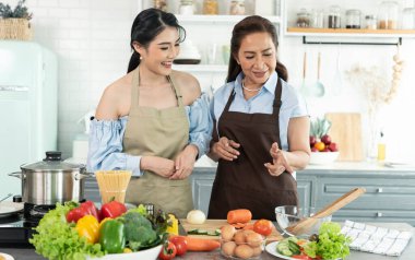 Mutlu Asyalı anne, kızına evde salata yapmayı öğretiyor. Aile aktivitelerinin tadını çıkarın..