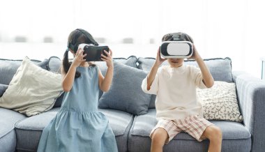 Asian child feeling excited while using 360 VR headset for virtual reality, Metaverse at home.