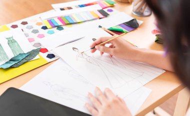 Beautiful asian Fashion designer drawing sketches for new collection. Designer creative workshop studio.