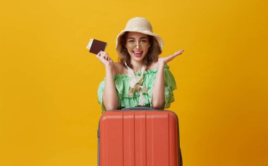 happy woman girl with suitcase and passport on yellow background. concept of travel.