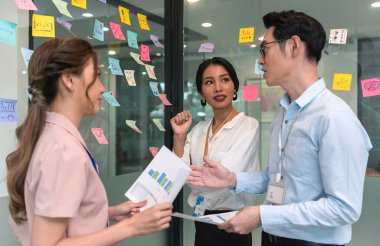 Asian business people meeting at office and use post it notes to share idea. Brainstorming concept. Sticky note on glass wall.