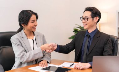 Asian businesspeople shake hands starting collaboration at negotiations, positive businesspeople gathered at office boardroom, partnership teamwork.