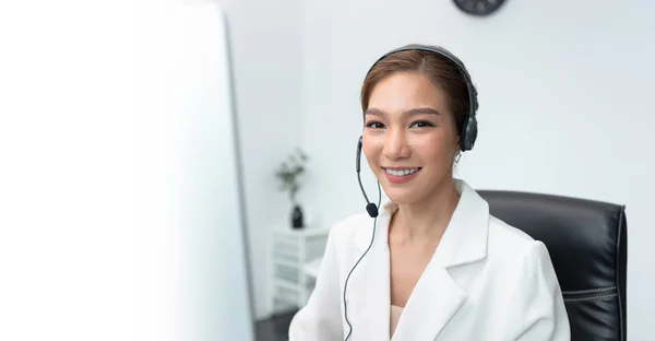 Asian woman Call center agent with headset working on support hotline in modern office with copy space.