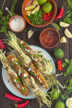 Meksika usulü ızgara mısır ve yemek masasında acı biber sosu.