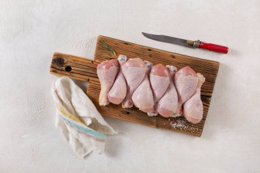 Baharatlı, biberiyeli ve biberiyeli kesme tahtasında çiğ tavuk budu.