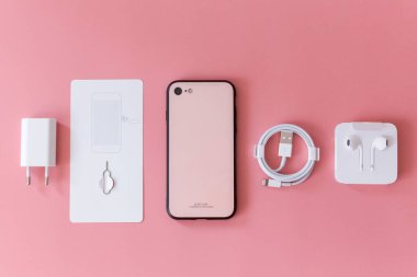 3 Nisan 2021, Kiev, Ukrayna, iPhone SE. Modern akıllı telefon aksesuarları ve pembe arka planda kulaklıklar.