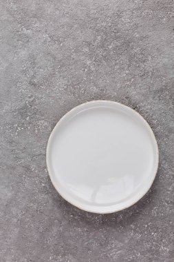 Gri beton arka planda boş beyaz plaka, yakın plan