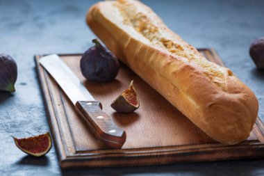 Çıtır ekmekli taze ekmek ve masada olgun incir meyveleri.