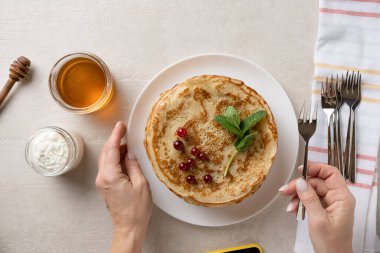Woman serves thin pancakes on the dining table for Shrove Tuesday, top view
