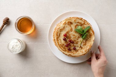 Woman serves thin pancakes on the dining table for Shrove Tuesday, top view