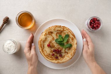 Woman serves thin pancakes on the dining table for Shrove Tuesday, top view
