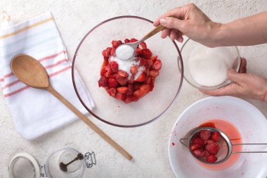 Evinin mutfağında çilek reçeli hazırlayan bir kadın.