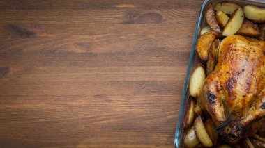 Kaz rostosu ya da ahşap bir arka planda pişmiş elmayla doldurulmuş tavuk, şenlikli bir Noel tarifi. Kırsal stil tasarımı. Kopyalama alanı olan üst görünüm.