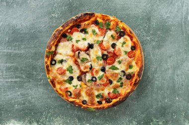 Yeşil taştan arka planda yeşillikleri olan lezzetli vejetaryen domates ve peynirli pizza.
