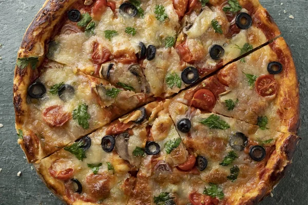 Yeşil taştan arka planda yeşillikleri olan lezzetli vejetaryen domates ve peynirli pizza.