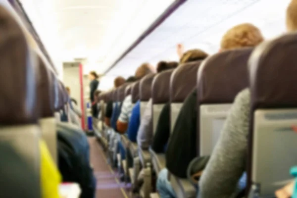 Blur background of passenger plane cabin with people sitting in armchairs, Plane travel concept