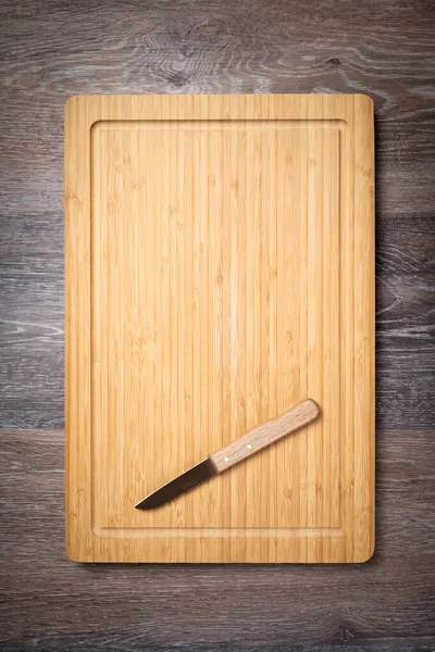 Wooden chopping board. Kitchen cutting board on wooden table, top view