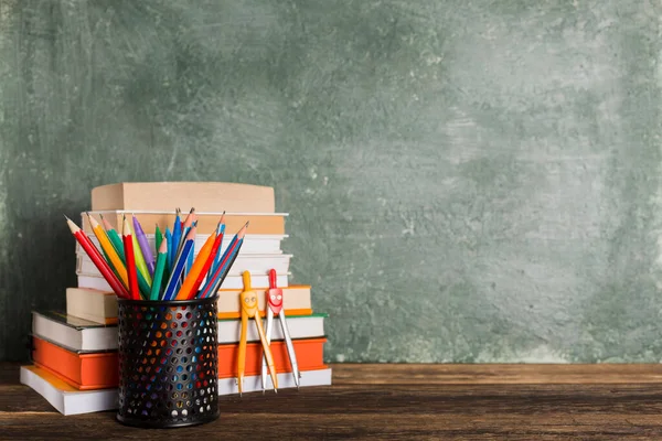 a Stack of books and stationery on the background of the school board. Education and back to school concept.