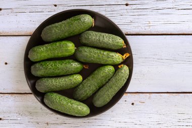 Bahçeden taze salatalıklar, açık ahşap arka planda, doğal ekolojik gıdalar.