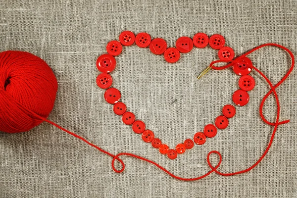 Corazón en forma de botones rojos, aguja e hilo —  Fotos de Stock