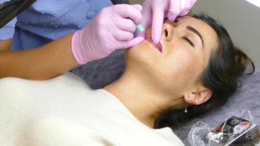 Kozmetik prosedürü. Kalıcı dudak makyajı. Güzellik uzmanı güzellik salonunda makyaj yapıyor.. 