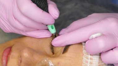 Kozmetik prosedürü. Göz kapaklarındaki okların kalıcı makyajı. Güzellik uzmanı güzellik salonunda makyaj yapıyor.. 