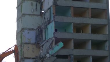 Bir kazıcı traktörü çökmüş bir evin beton kalıntılarını bir kovayla kazıyor..