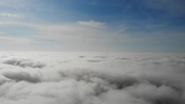 Flying over the clouds. White gray clouds and blue sky.