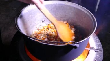 Gulaş baharat ve etle hazırlandı. Sıcak bir yemekten çıkan buhar. Kazanda bir mutfak var. Mutfak spatulasıyla karıştır. Kamp ateşi yemeği..