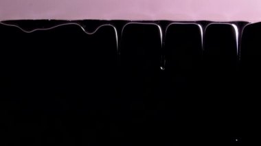 Sıvı damlaları yüzeyden aşağı akıyor. Siyah arka planda jel. Kalın yapışkan madde. Siyah arkaplanda jel.