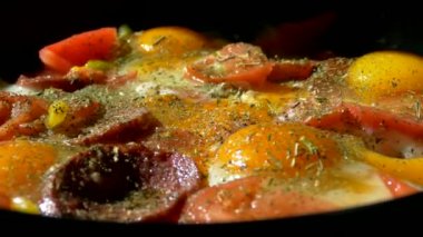 Tavada omlet. Yumurtalı, sebzeli ve sosisli bir tabak. Hızlı bir kahvaltıdan buhar yükseliyor.