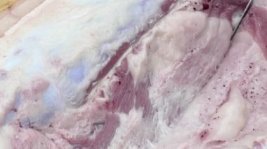 Domuz leşini bıçakla kes. Kasap, leşi yağdan ayırır. Çiftlikte bir et dükkanında çalışıyorum.