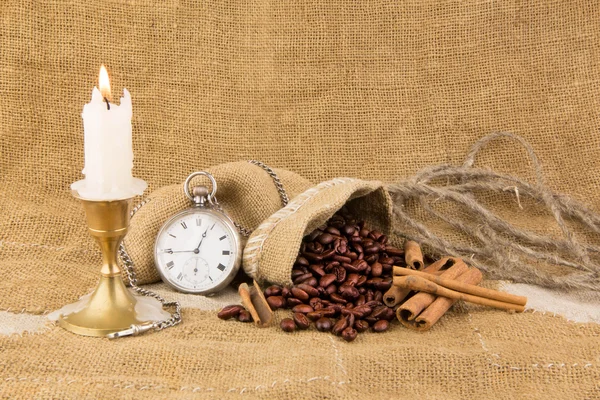 Grains of coffee of a stick of cinnamon with a pocket watch and