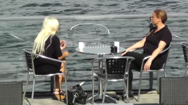 Два молодих красивих дівчат в кафе на відкритому повітрі на літній море — стокове відео