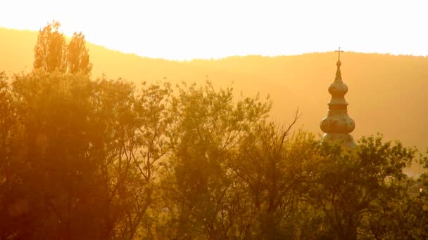 Schönheit Sonnenuntergang über der Kirche im Frühling mit fliegenden Pflanzenblättern und Blüten in der Luft — Stockvideo