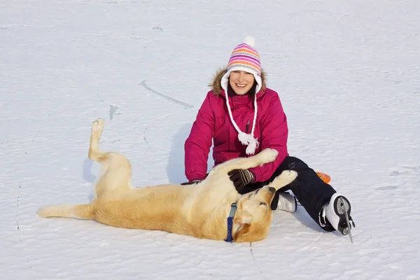 Девушка на коньках играет с собакой — стоковое фото