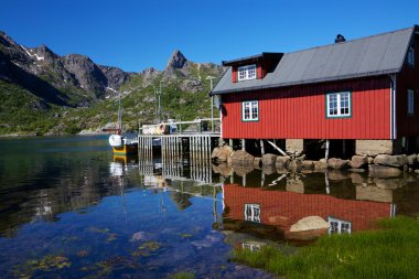 Fishing hut reflecting in fjord clipart