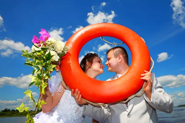 Wedding.Groom and bride with a lifebuoy — Stock Photo, Image