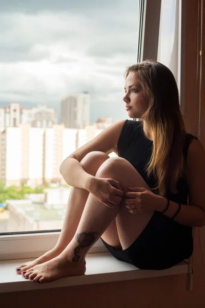 Porträt einer schönen Frau, die durch das Fenster schaut — Stockfoto