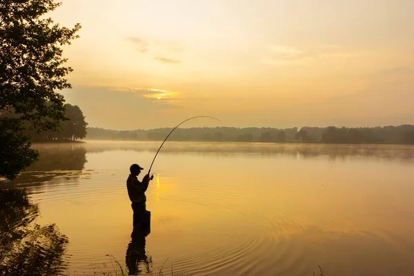 日出时钓到鱼的垂钓者 — 图库照片